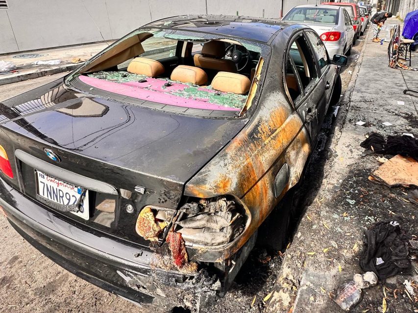 A burned out car is parked on a street.