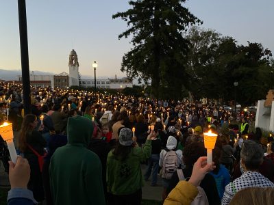 A crowd of people holding candles for a vigil.