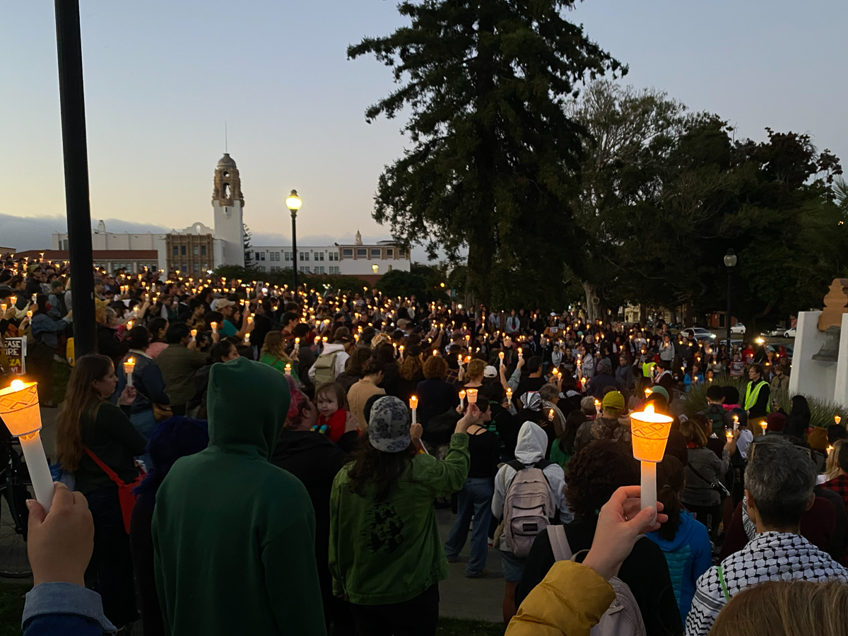 A crowd of people holding candles for a vigil.