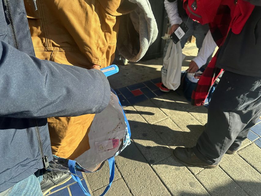 A group of people standing on a sidewalk.