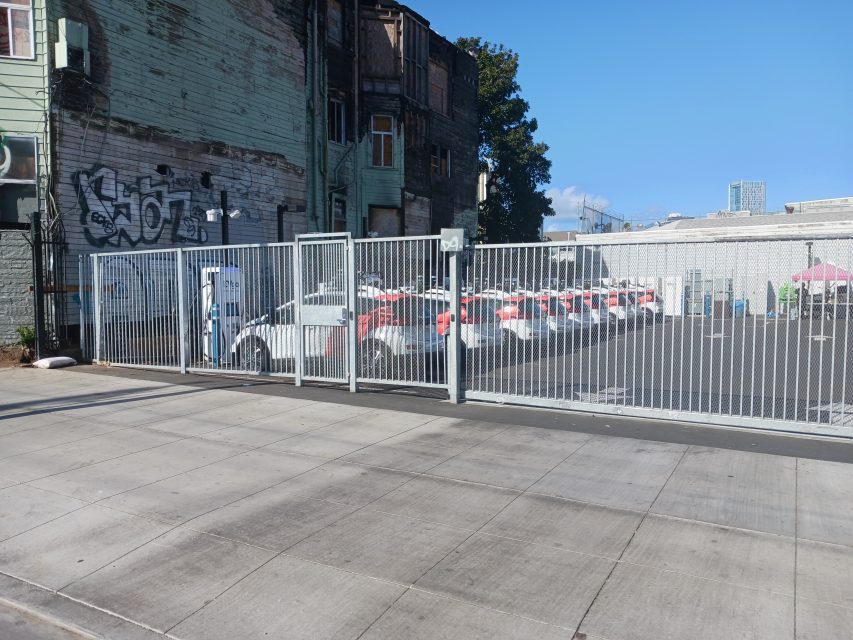 A fleet of Cruise cars parked in a parking lot behind a fence.