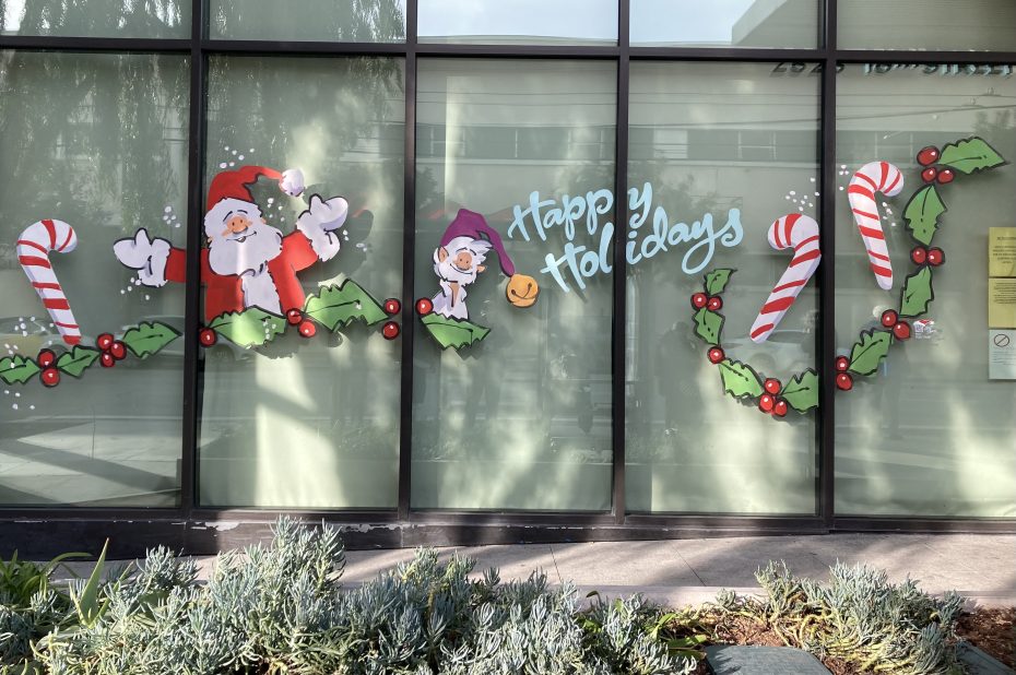 Santa Claus and candy canes are painted on the windows of a building.