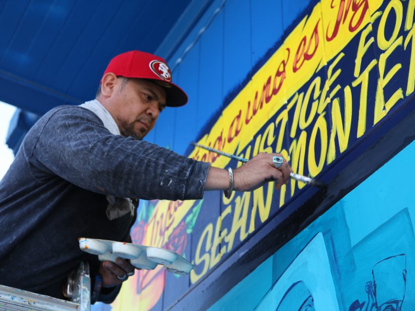 A man painting a mural on a building.