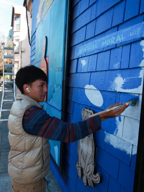 A teenage painting a blue wall.