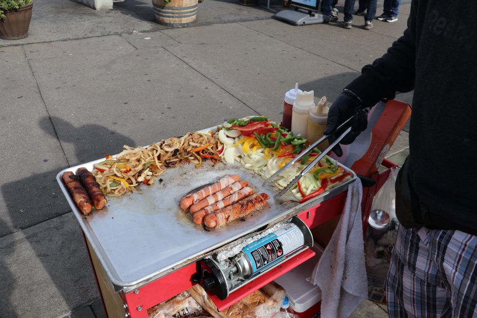 Someone grilling sausages on a mobile cart.