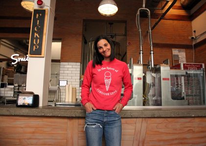 A woman in a red sweatshirt standing in front of a counter.