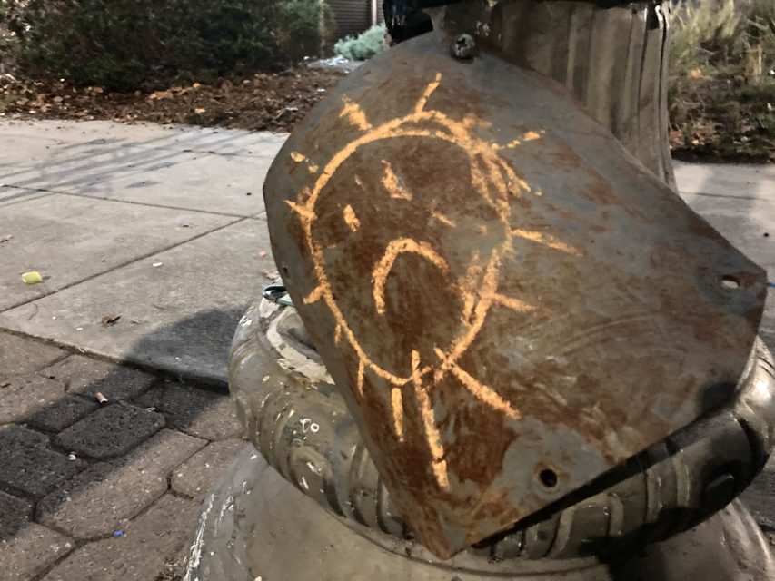 A planter by the street with a sad face on it.
