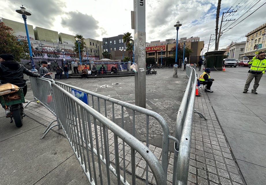 A man riding a bike past vendors on a bustling city street.