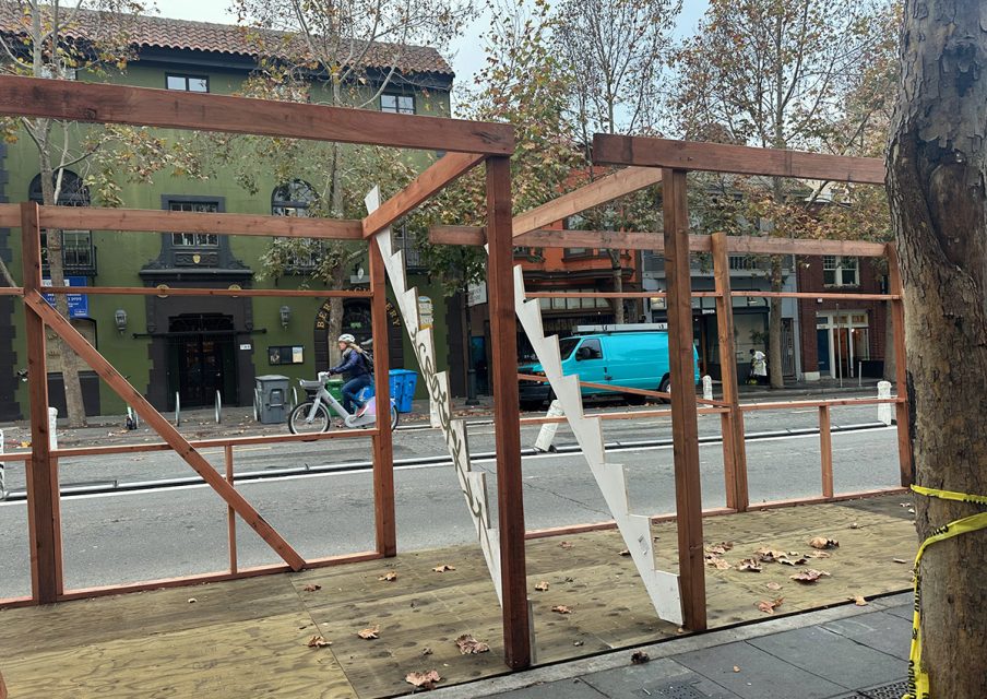 A wooden structure is being built on the side of a street.