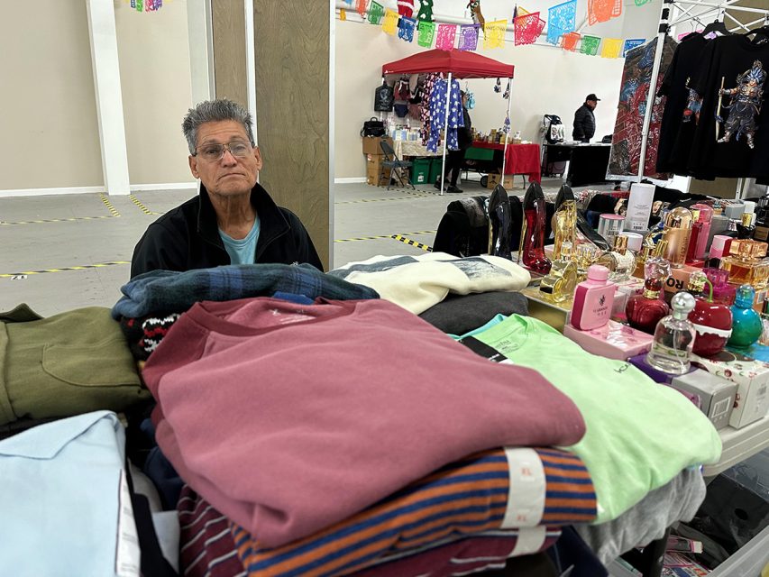 A woman is selling clothes at a flea market.
