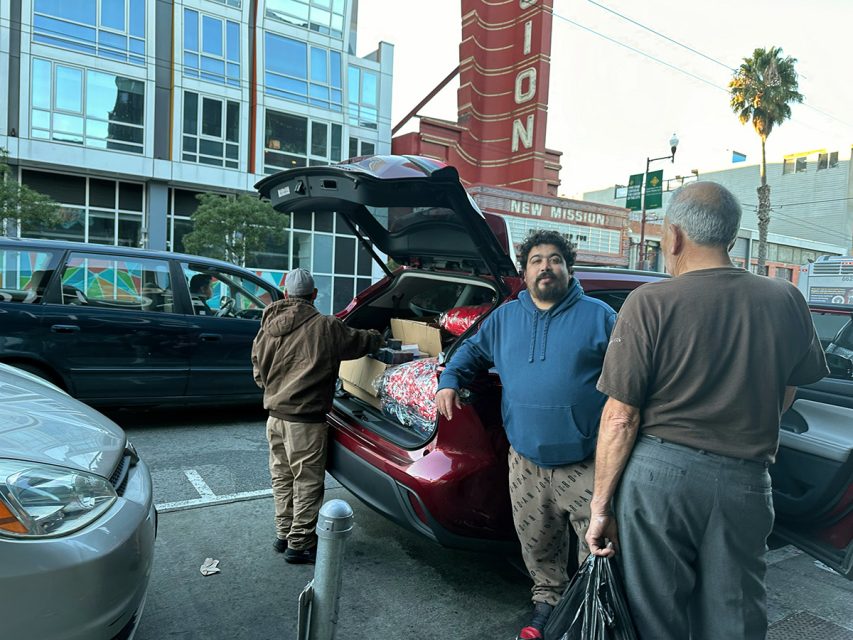 One of Mission Street's vendors is opening the trunk of a car.