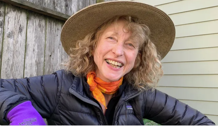 A woman wearing a hat and gloves is smiling.