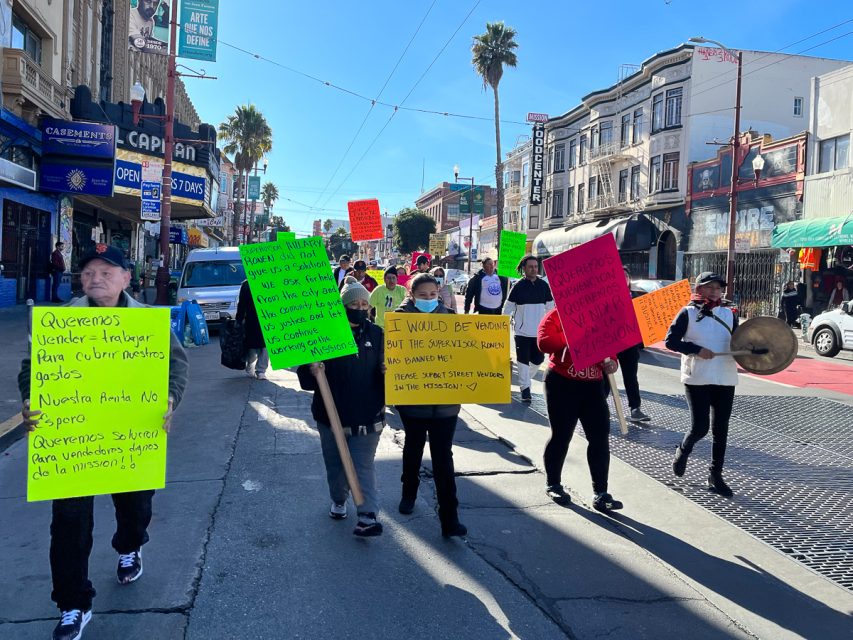 A group of vendors holding signs, marching down Mission Street and protesting the Mission street-vending ban.