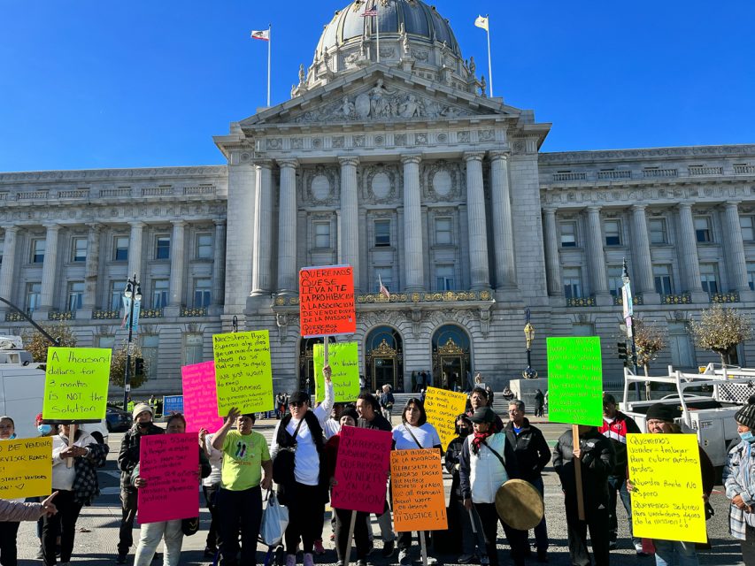 A group of vendors holding signs in front of San Francisco city hall, protesting Supervisor Hilary Ronen's 90-day street vending ban on Mission Street.