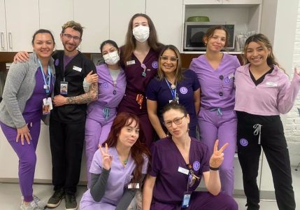 A group of nurses from Planned Parenthood in purple scrubs posing for a photo.