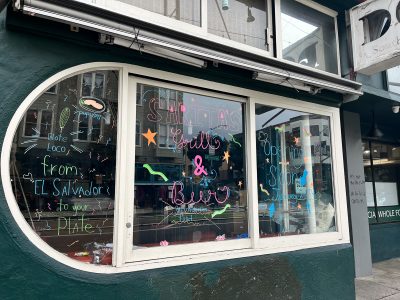 The glass window of the new restaurant on Valencia Street called Sarita's Grill & Beer. The restaurant's name written on it.