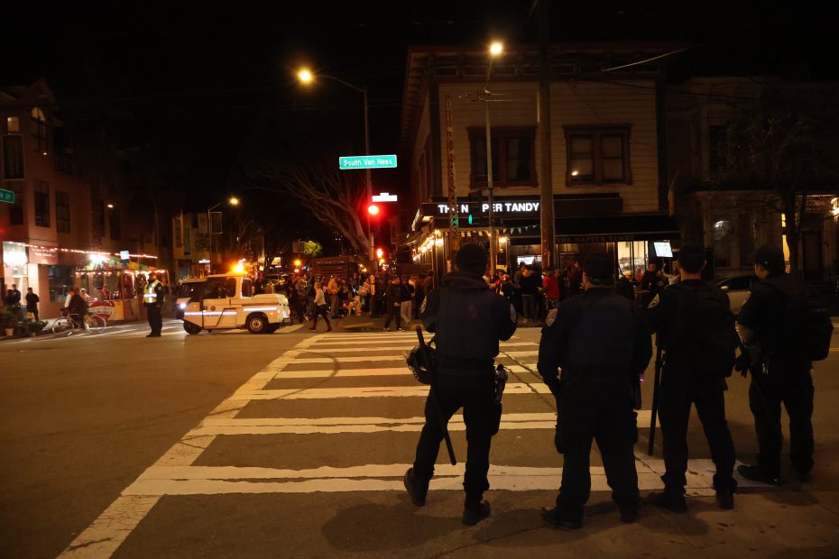 A group of police officers standing on a street at night.