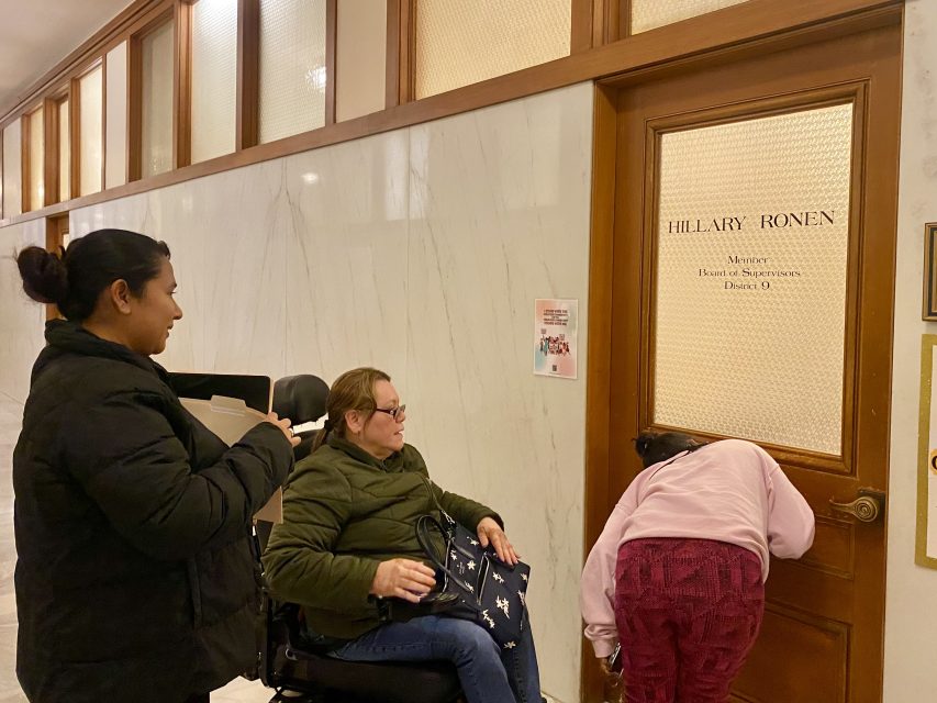 A woman in a wheelchair is standing in front of a door.