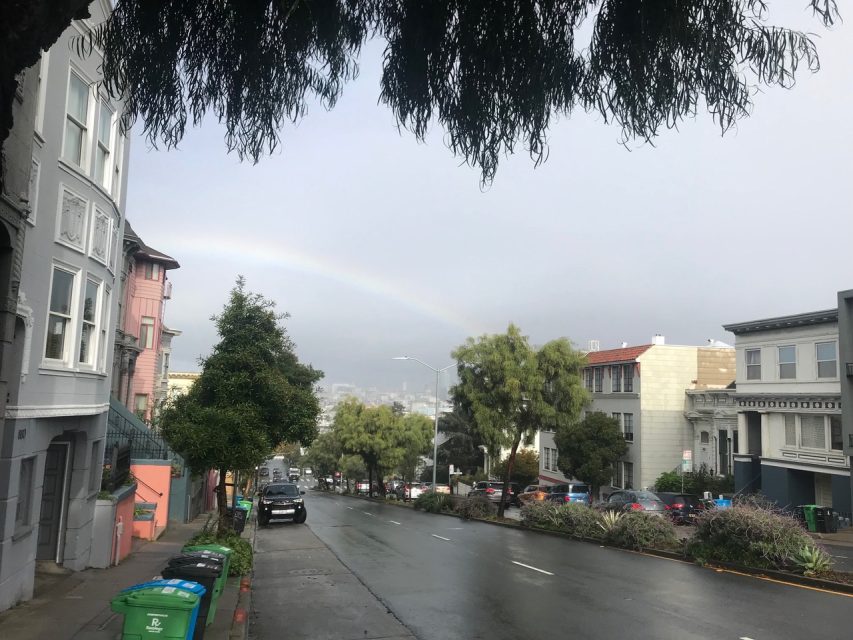 A rainbow is seen over a street in san francisco.