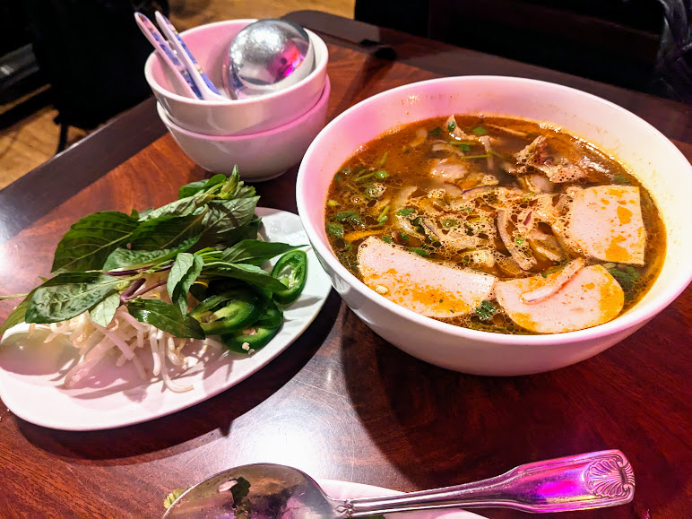 A bowl of noodle soup on a wooden table.