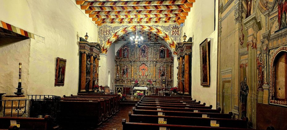 The interior of a church with wooden pews and painted walls.