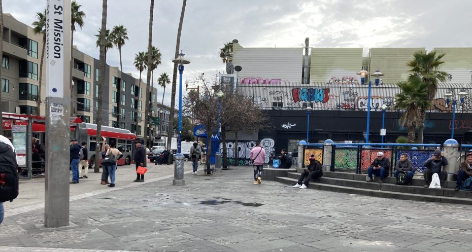A group of people walking on a sidewalk in front of a building.