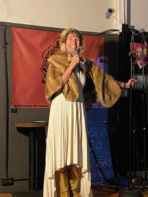 A woman in a white dress standing in front of a microphone.