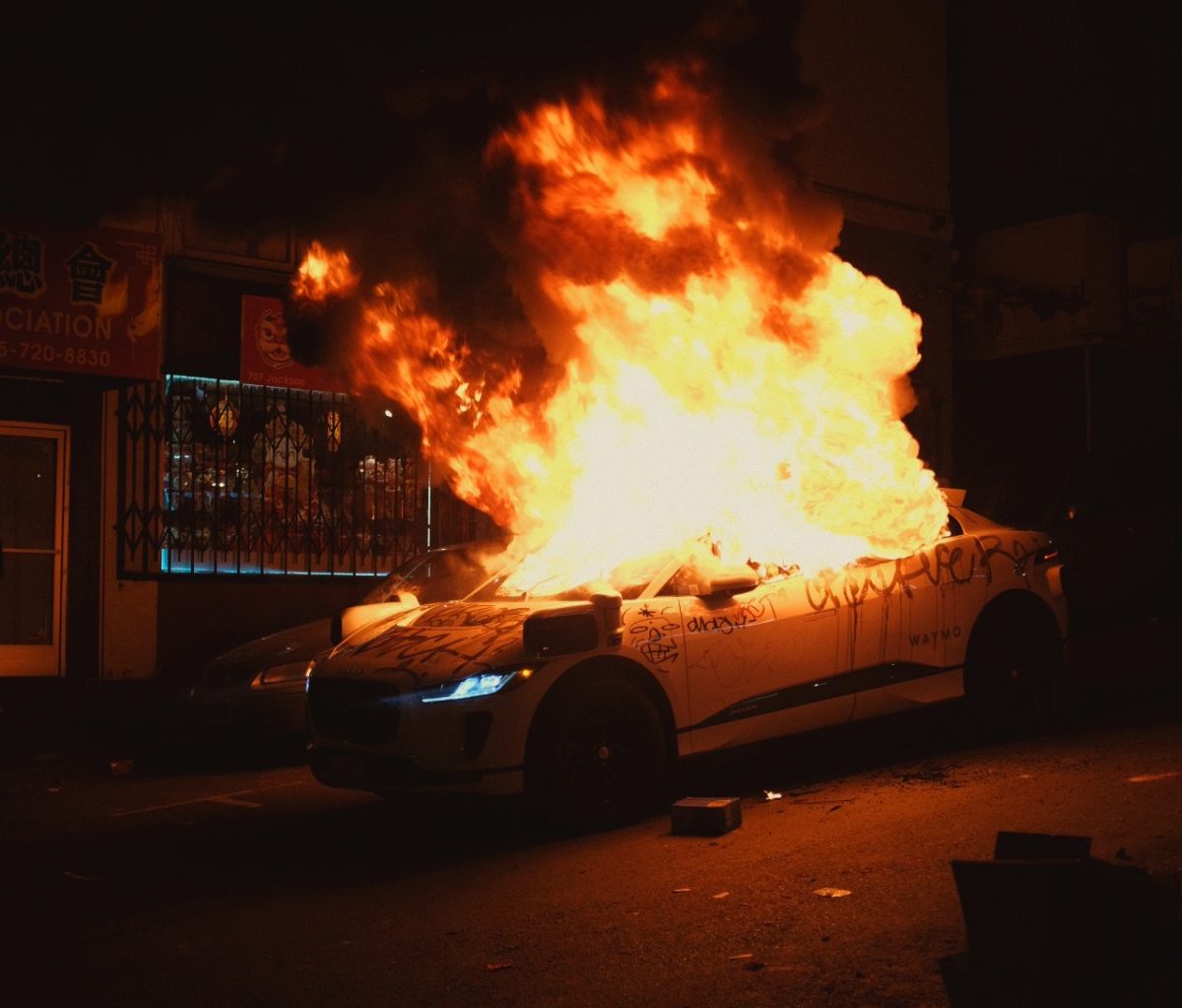 A car is on fire in front of a building.