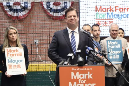 A group of people standing in front of a baseball field holding signs.