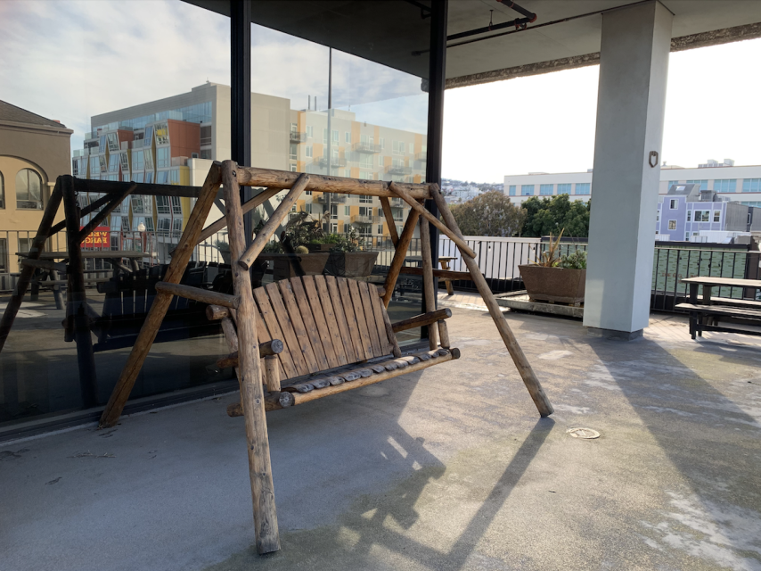 A wooden swing on a patio.
