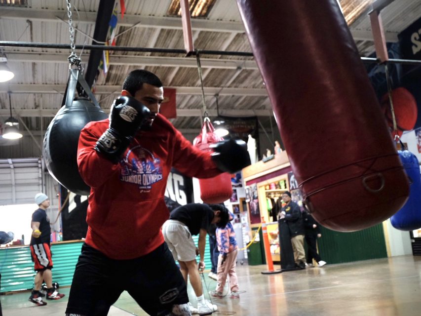 A man is punching a boxing bag in a gym.