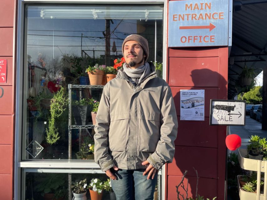 A man standing in front of a flower shop.