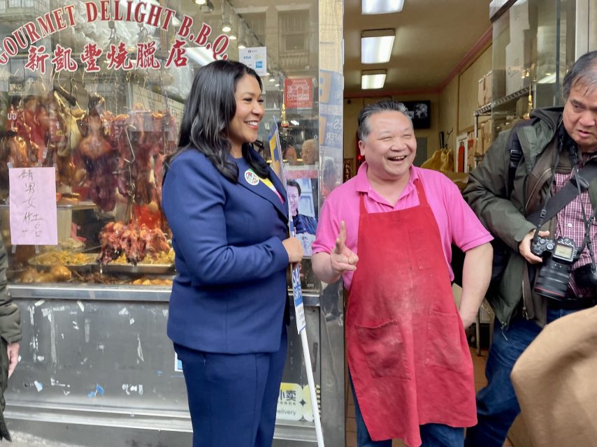 Mayor London Breed standing next to a shopowner in Chinatown, shaking hands