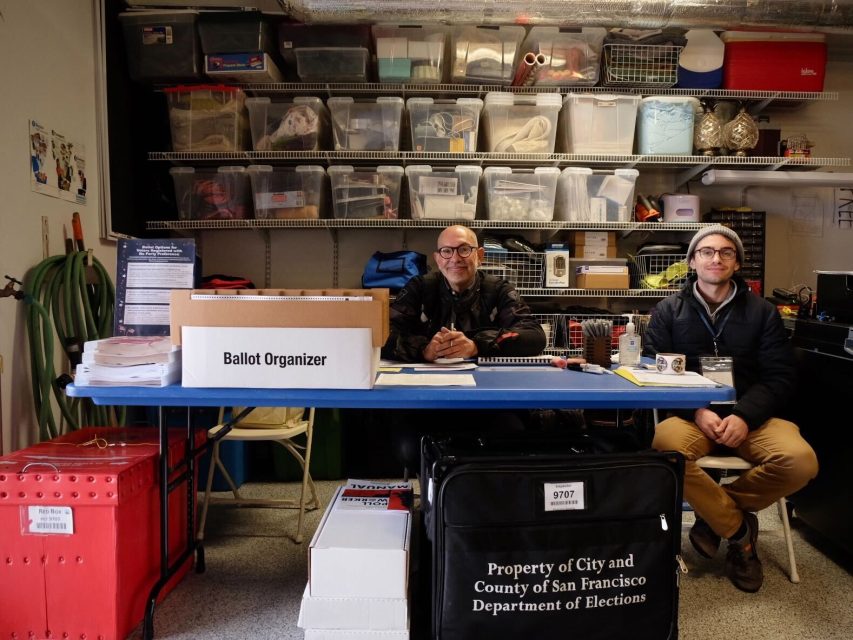Poll workers at 731 Judah St. seated behind a table with ballots