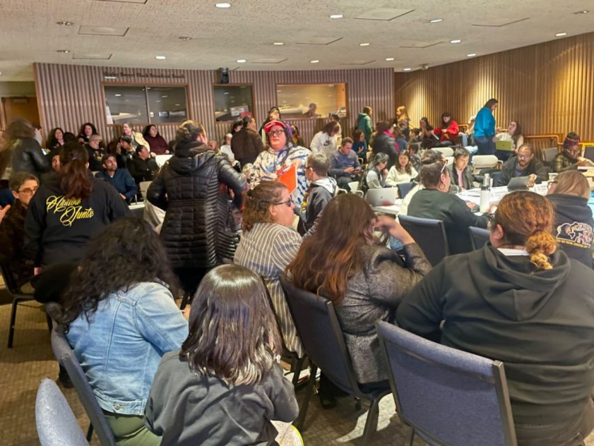 A large group of people sitting at tables in a room.