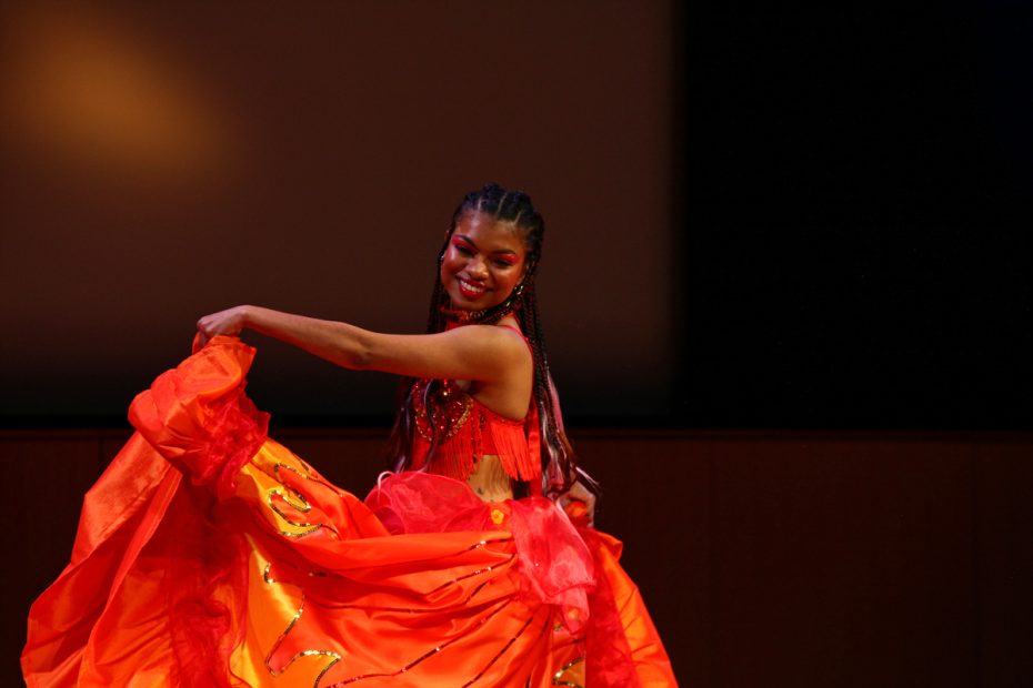 Dancer in vibrant red attire performing on stage.