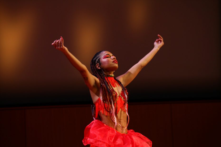 Dancer performing on stage in a red costume.