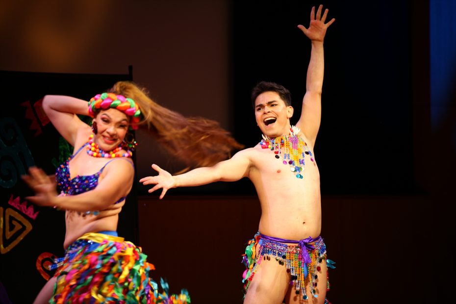 Two Carnaval dancers performing energetically on stage in colorful costumes.