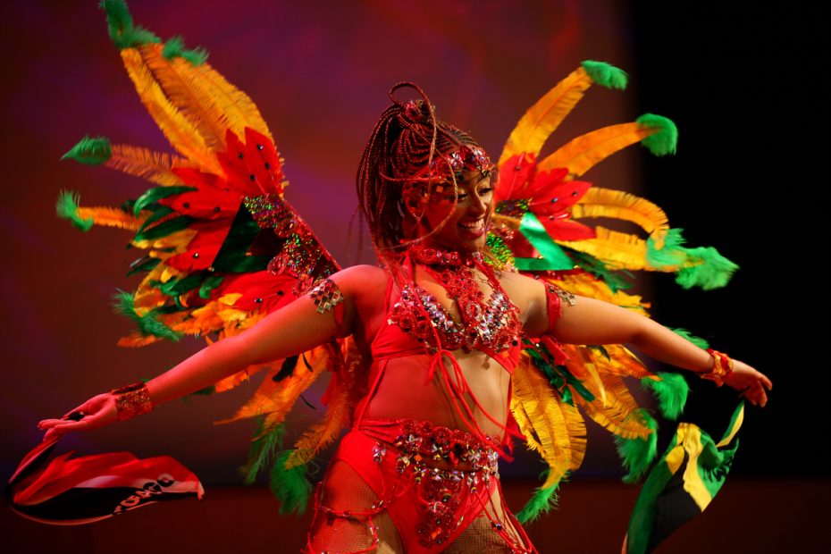 Performer in colorful feathered costume dancing on stage.