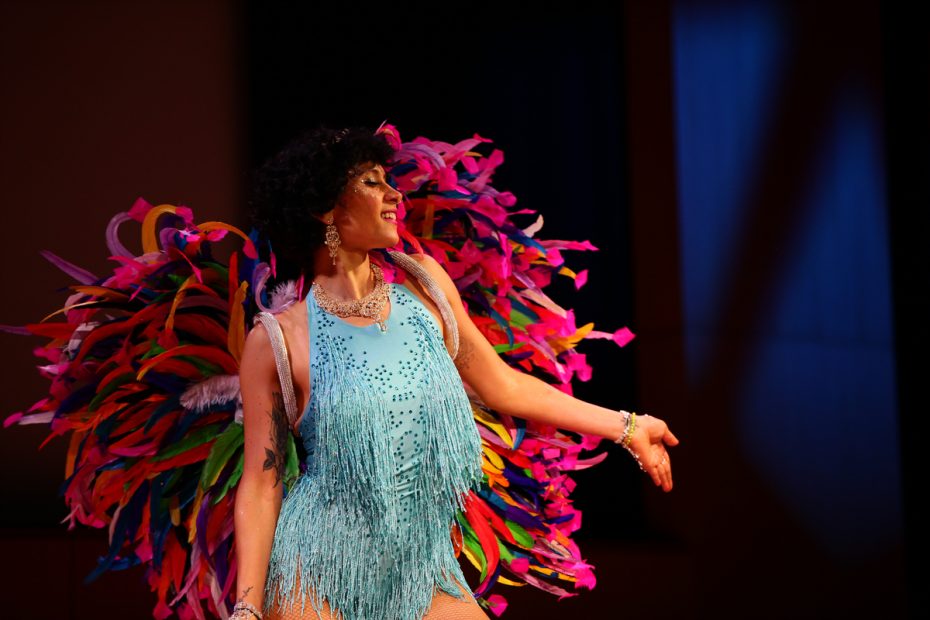 Performer in colorful feather costume on stage.