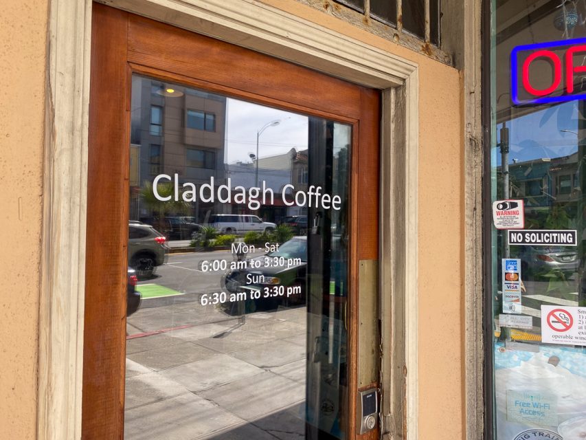 Glass door of Claddagh Coffee with posted business hours.