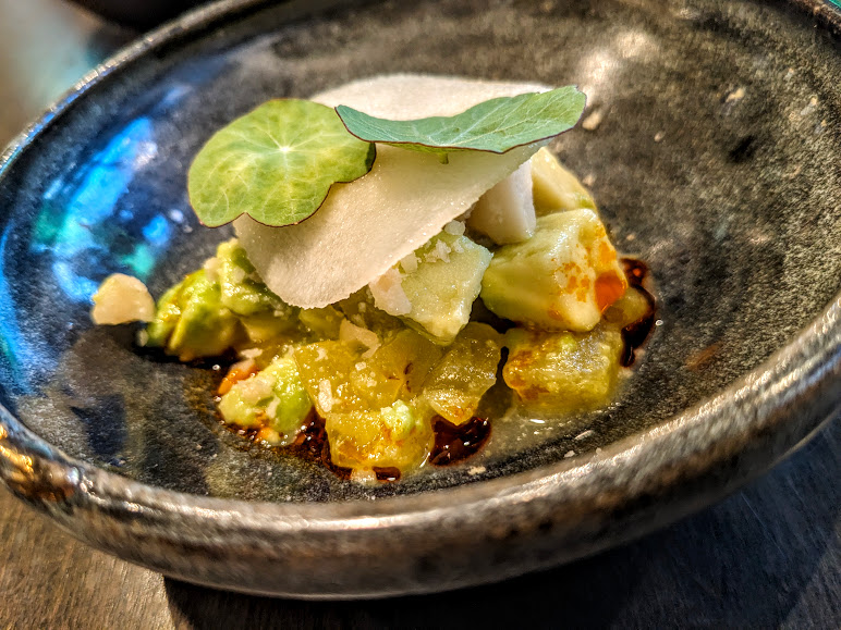 Gourmet dish featuring avocado and garnishes, served on a ceramic plate at Foliage.