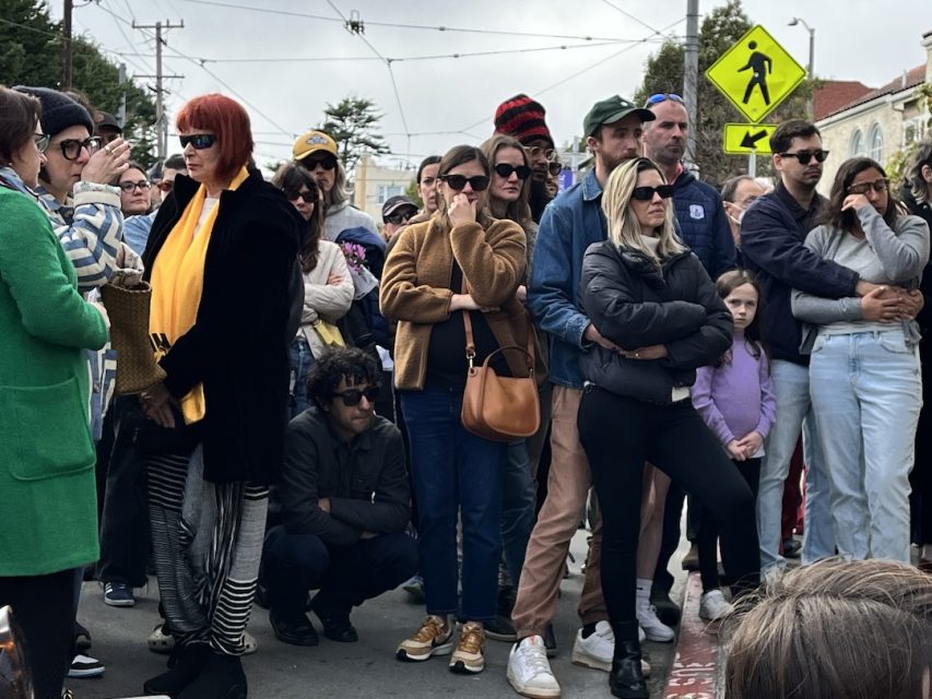 Crowd of people watching an event on a cloudy day.