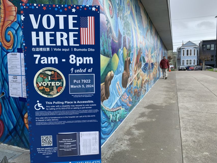 a sign reading "vote here" at Garfield Park