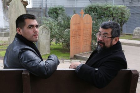 Vincent Medina and Andrew Galvan sit near a memorial for their ancestors, Jobocme and Poylemja, in the Mission Dolores cemetery.