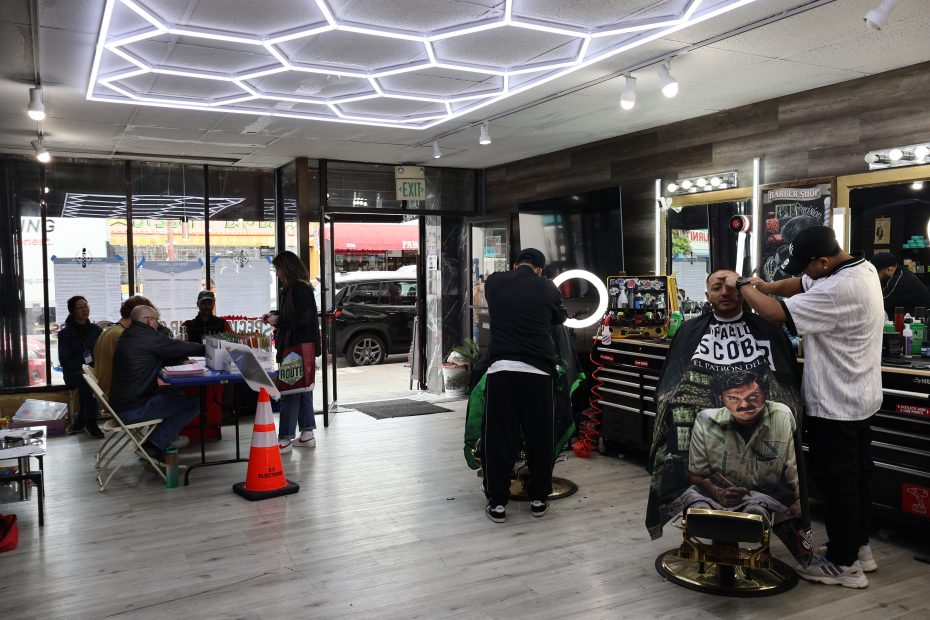 Ana's Salon in the Mission, with barbers lined up on the right and a table with voting materials on the left