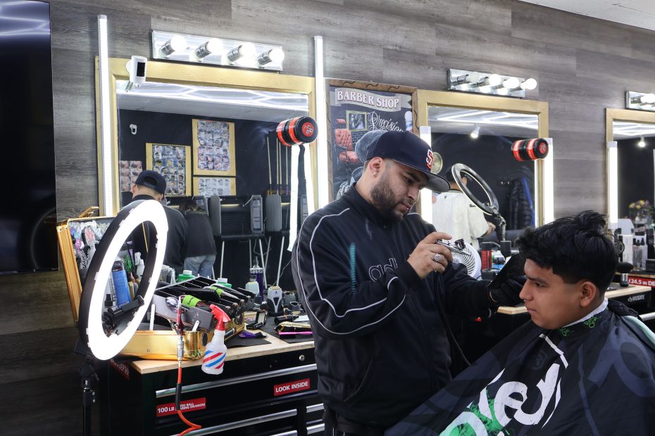 A barber cutting a young boy's hair at Ana's Salon in the Mission