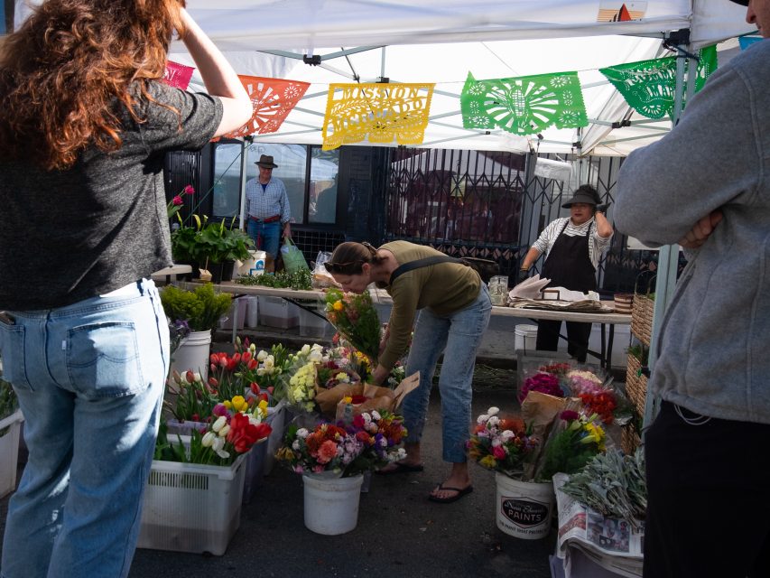 Woman browsing flowers at a local outdoor market stall.
