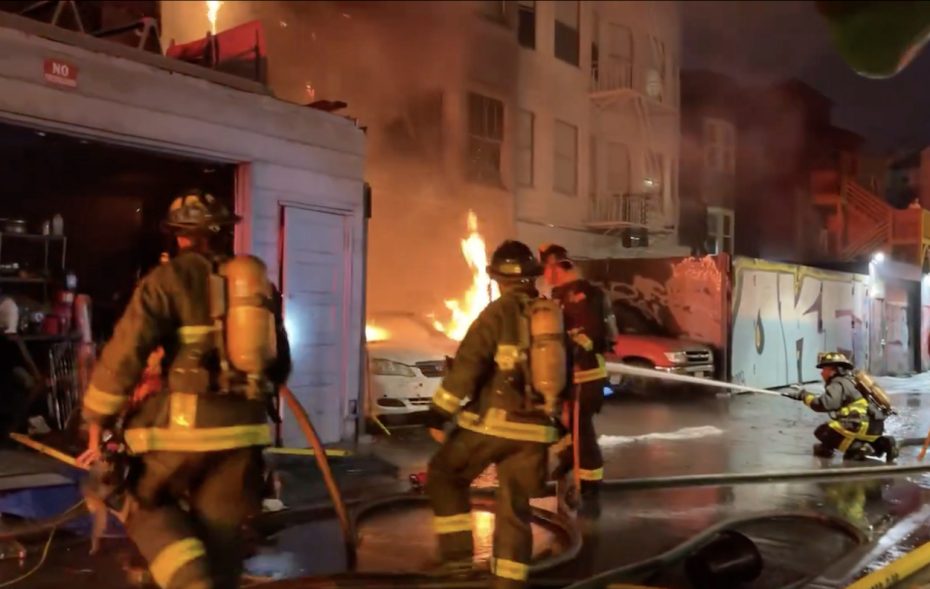 Firefighters responding to a blaze in a residential area at night.