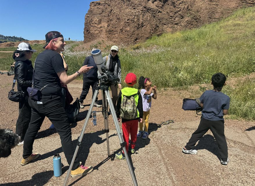 Group of people with children participating in an outdoor birdwatching activity.